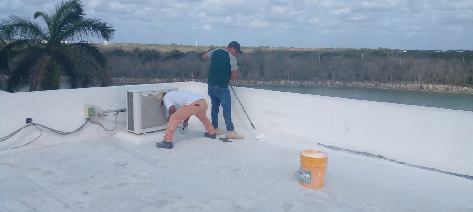 Cuadrilla aplicando sistema de impermeabilización con rodillo en azotea, Cancún